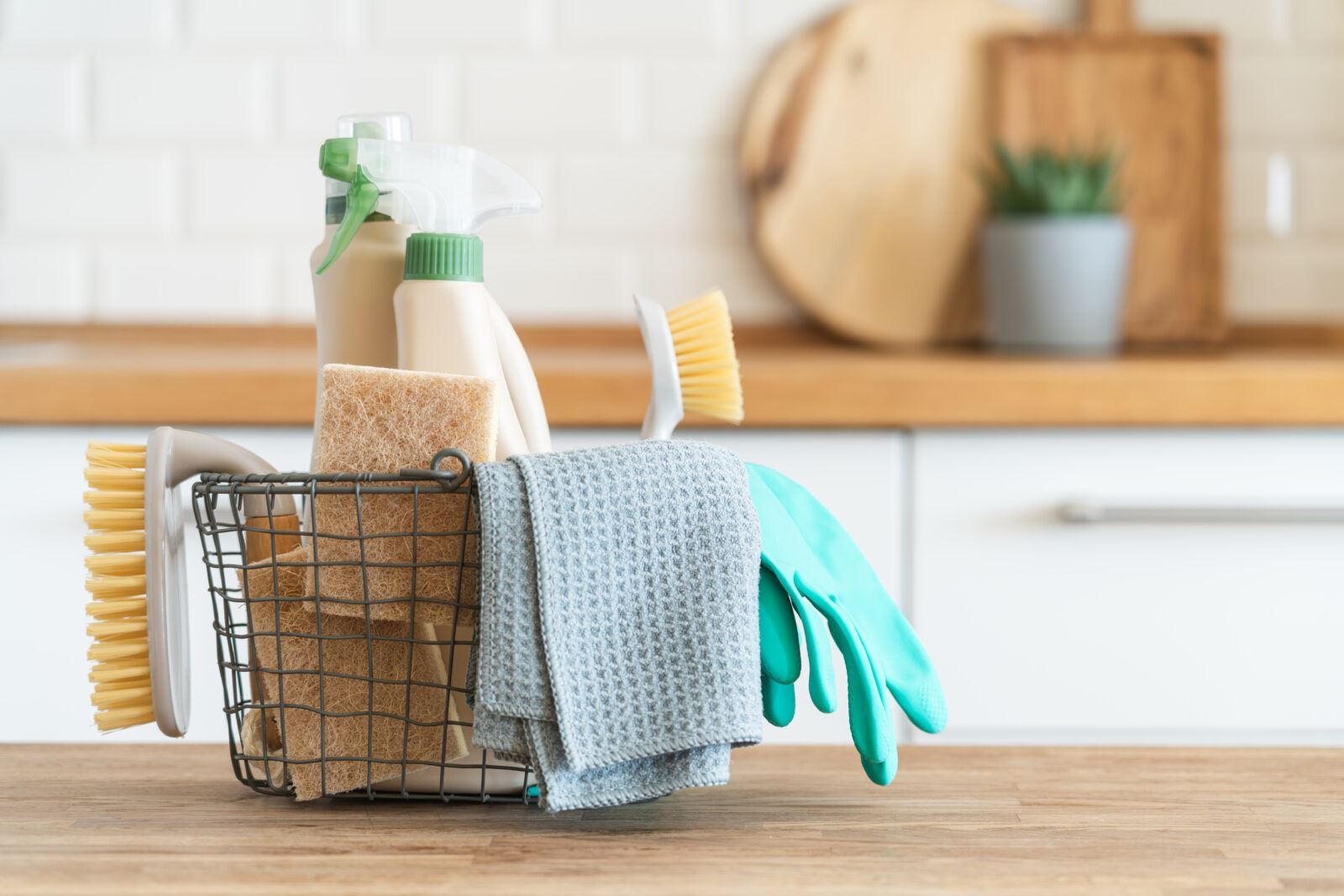 A wire basket of cleaning supplies sitting on a wood counter top