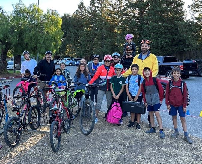 A group of school-aged children and parents biking and walking to school