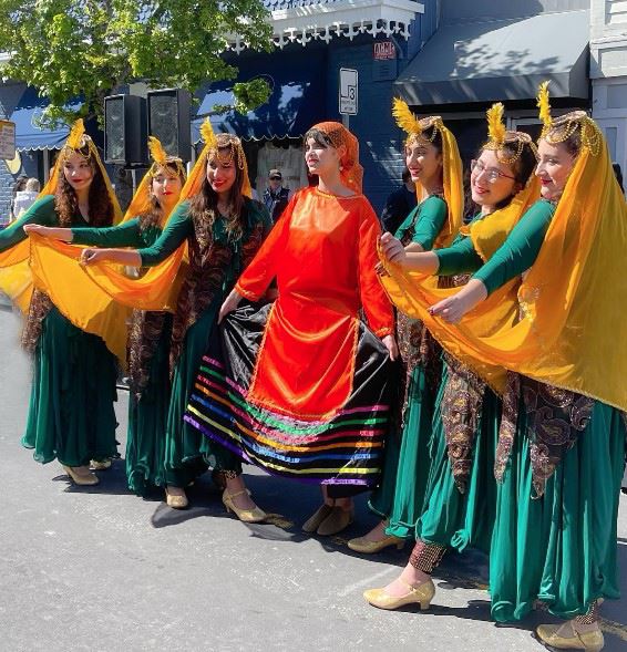 A group of dancers wearing traditional Persian costumes standing in a row on Main Street in Tiburon